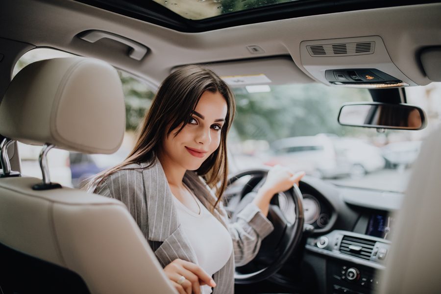 Back view of an attractive business woman looking over her shoulder while driving a car