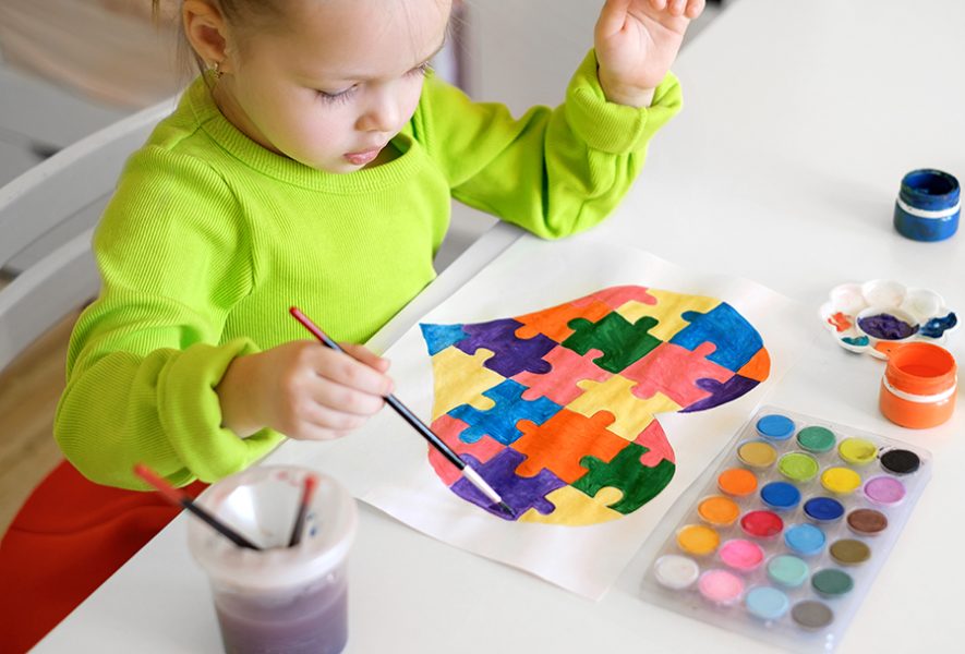 Baby paints with watercolor paints the generally accepted international symbol of autism - a heart made of colorful puzzle pieces. Drawing on the theme of tolerance, support and mutual understanding