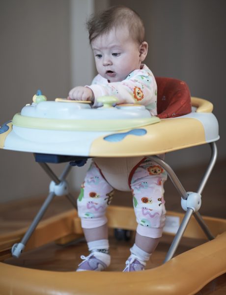 cute little baby learning to walk in walker at home