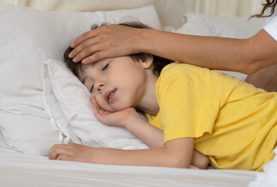 Caring mother checking kid body temperature touch forehead of small peaceful sleeping boy in bed after serious disease illness and fever. Loving parent hand in son head. Child healthcare and treatment