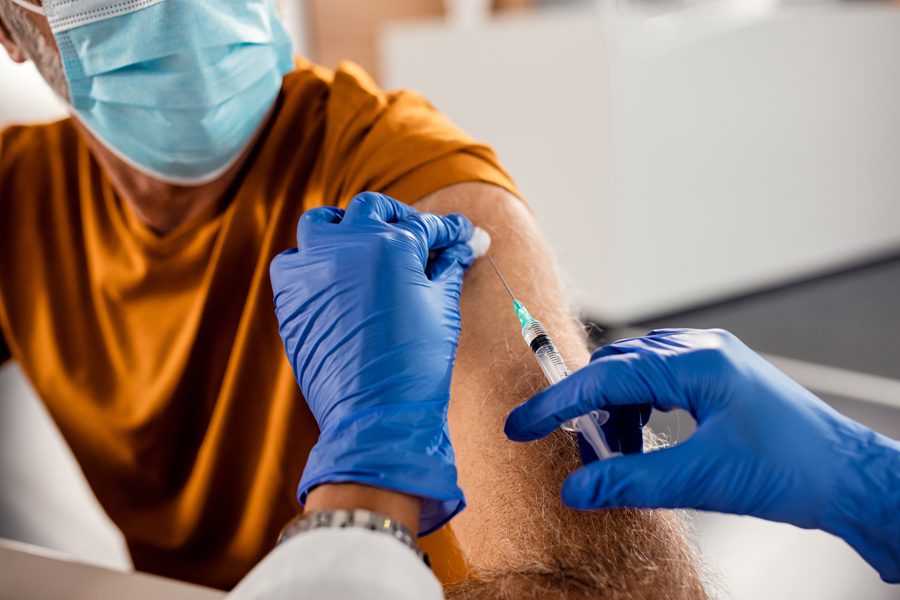 Close-up of mature man receiving vaccine at the hospital during coronavirus pandemic.