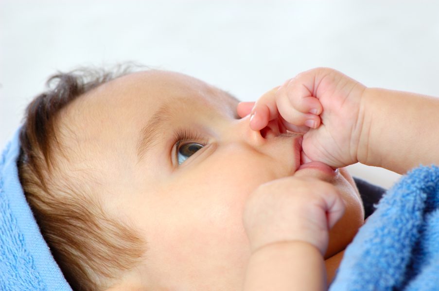 Close-up of a laughing little four month old girl looking at her mom. The concept of cute little innocent children. Caring and love concept