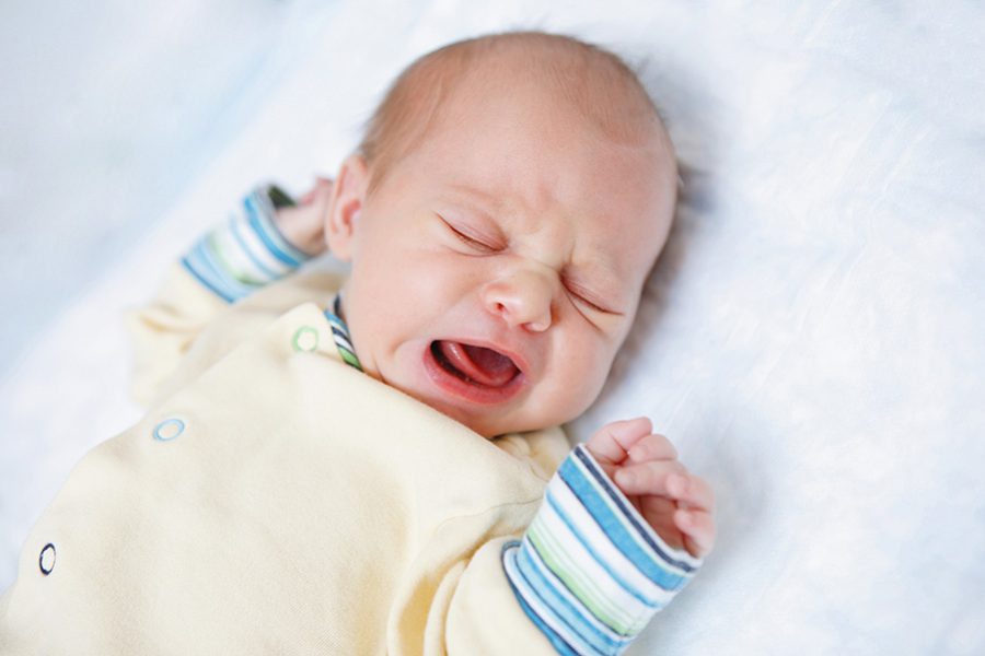 Cute newborn baby lies and cries. Happy childhood. Parental care.
