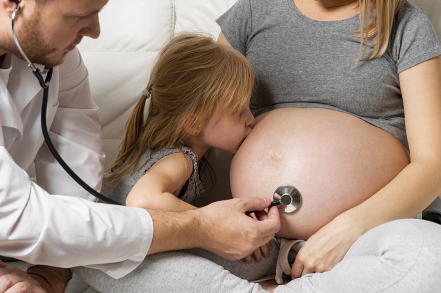 front-view-doctor-listening-pregnant-mother-belly