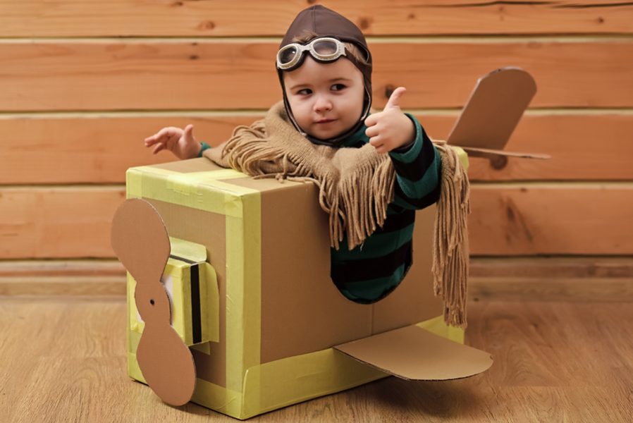 Funny child pilot flying a cardboard box. Child dream. aircraft construction, education. Thumbs up