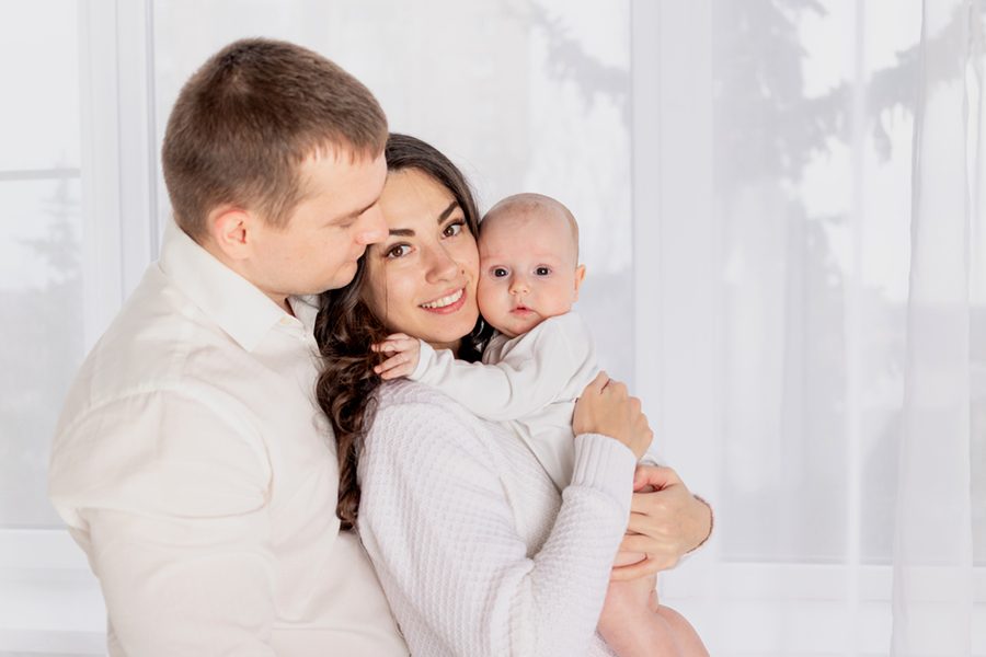 happy family mother and father hold a newborn baby at home, the concept of happy loving family, lifestyle