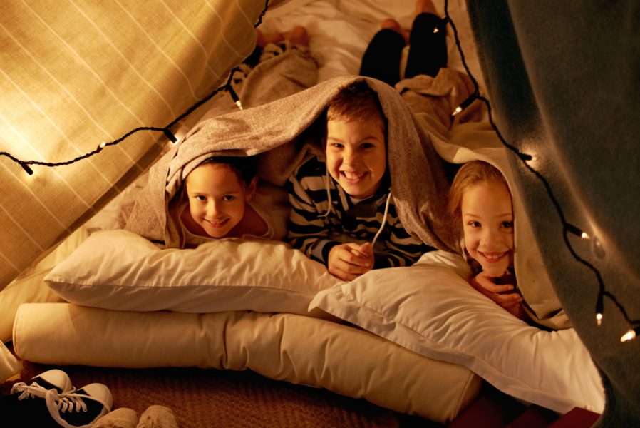 Shot of three young children playing in a tent together.