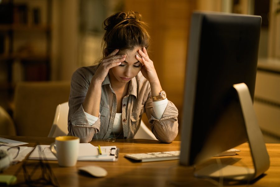 Young woman having a headache after working on a computer at night at home.