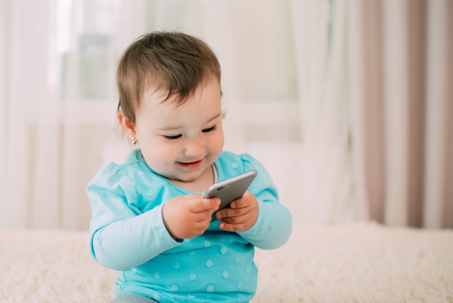 a little girl with a smartphone phone in her hands sits and presses very sweet