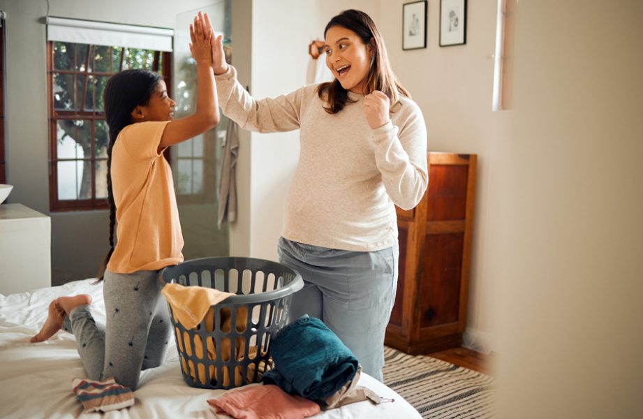 Mother, child and high five for laundry basket, housework or helping with chores together at home. Happy mom and daughter celebrating for clean clothing, washing or victory for done or finished work.