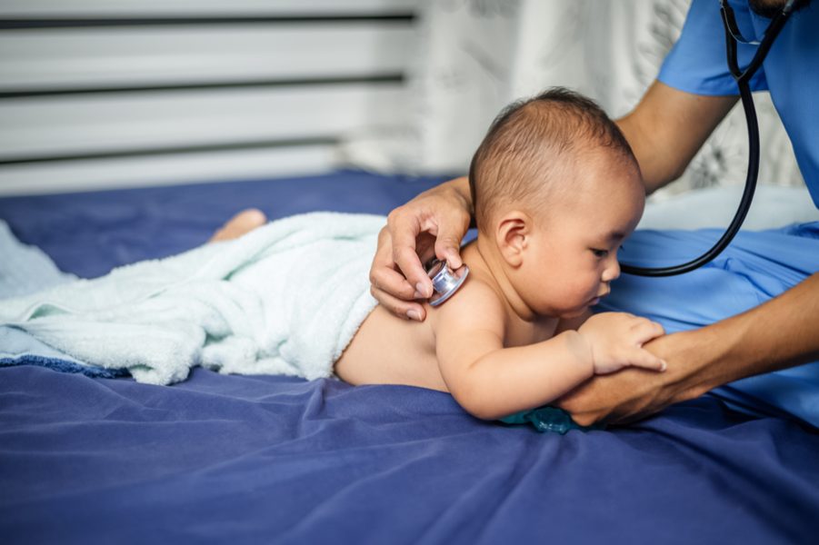 Asian Doctor examining little baby with stethoscope in clinic. Baby health concept