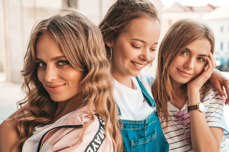 Portrait of three young beautiful smiling hipster girls in trendy summer clothes. Sexy carefree women posing on the street background.Positive models having fun.Hugging