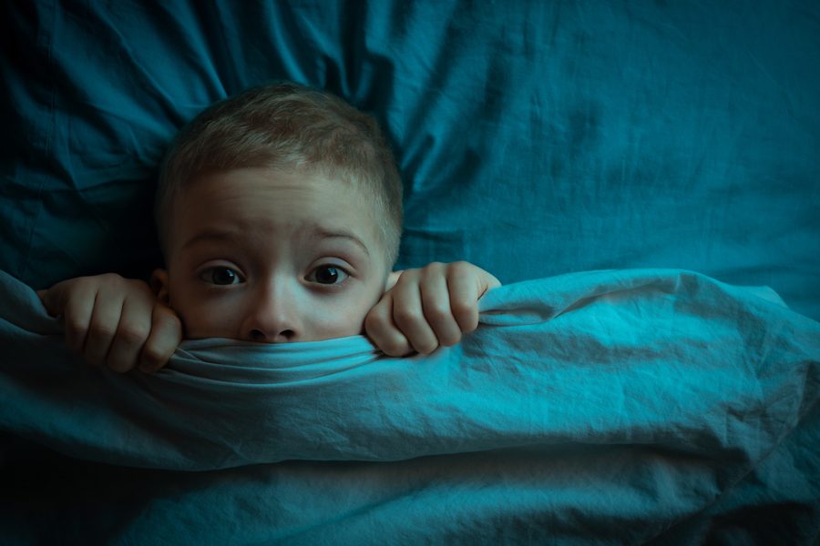 boy in bed with his eyes open. the child is afraid of the dark. tormented by nightmares and terrible dreams in children