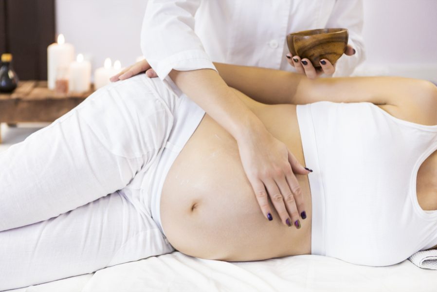 Young pregnant woman have massage treatment at spa salon