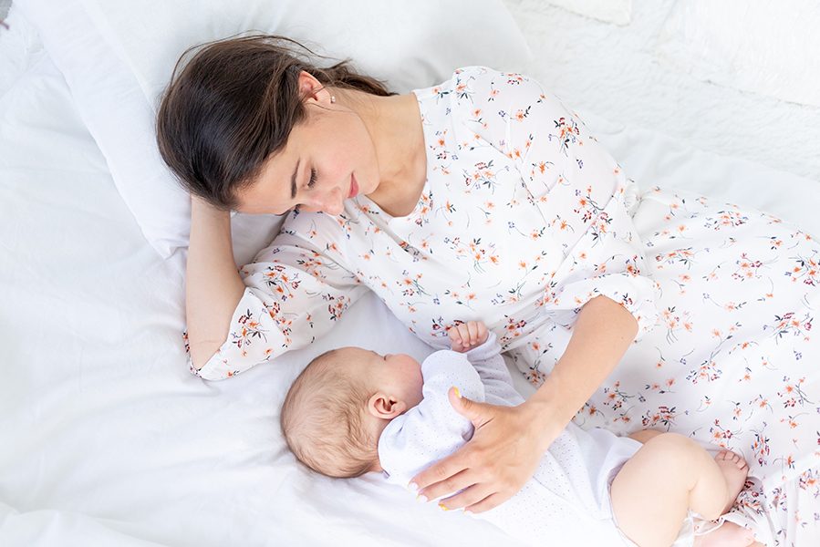 mom and newborn baby sleep together, mom puts baby to sleep on the bed in the bedroom, the concept of motherhood and healthy sleep