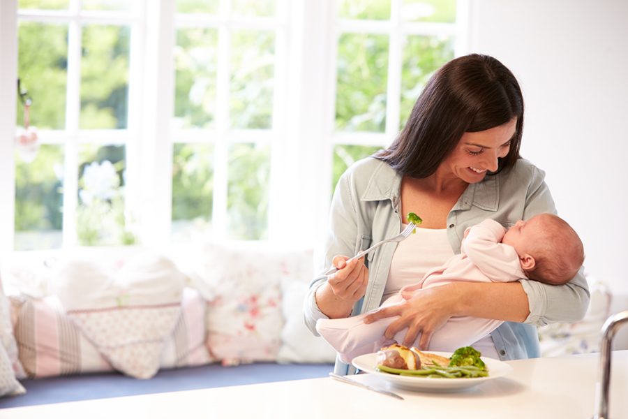 Mother With Baby Eating Healthy Meal In Kitchen