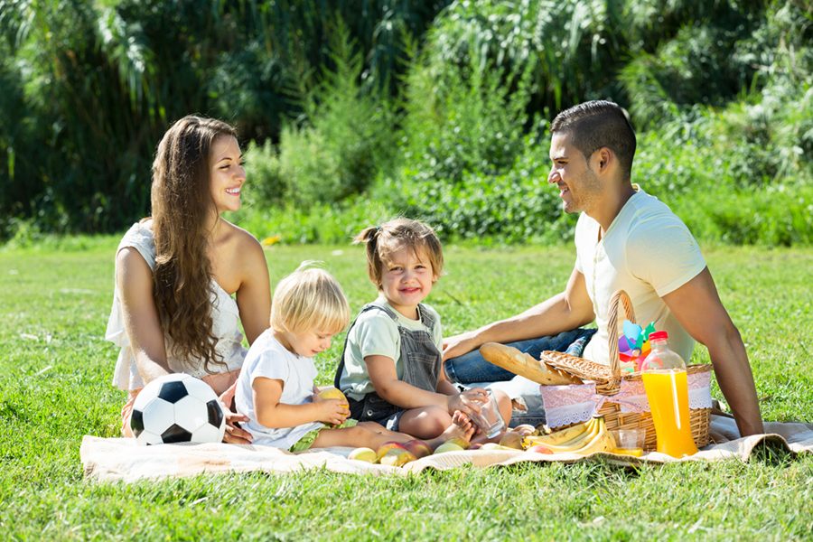 happy parents with little daughters having holiday with picnic