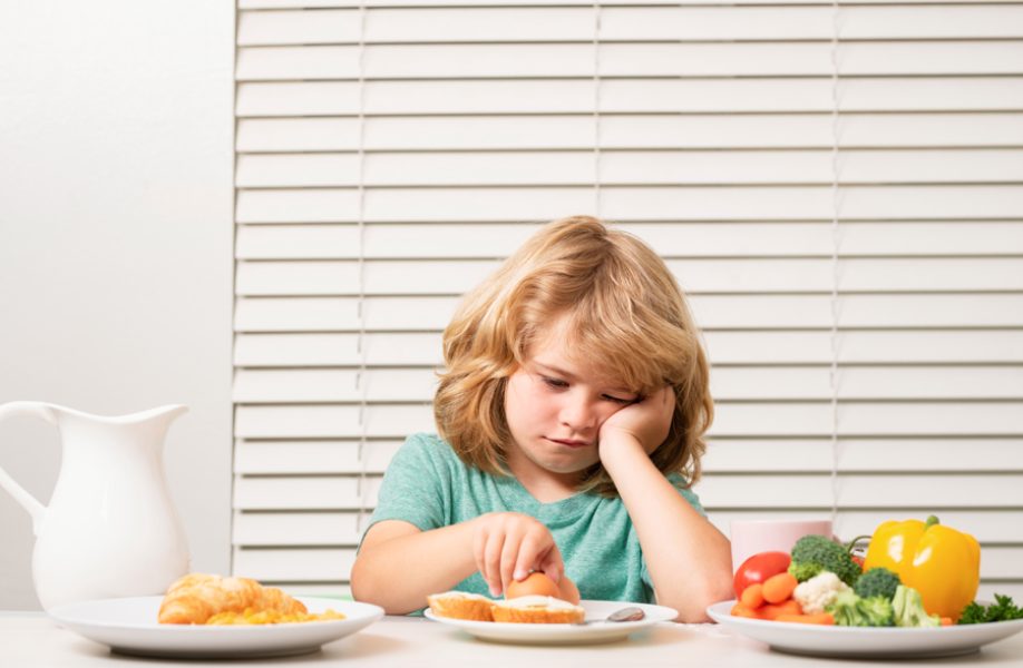 Portrait of kid with no appetite. Concept of loss of appetite. Child eats organic food. Healthy vegetables with vitamins. Proper kids nutrition concept