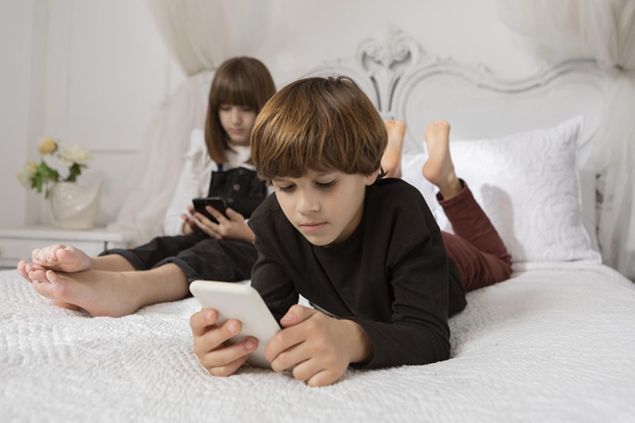 siblings-in-bedroom-with-phone