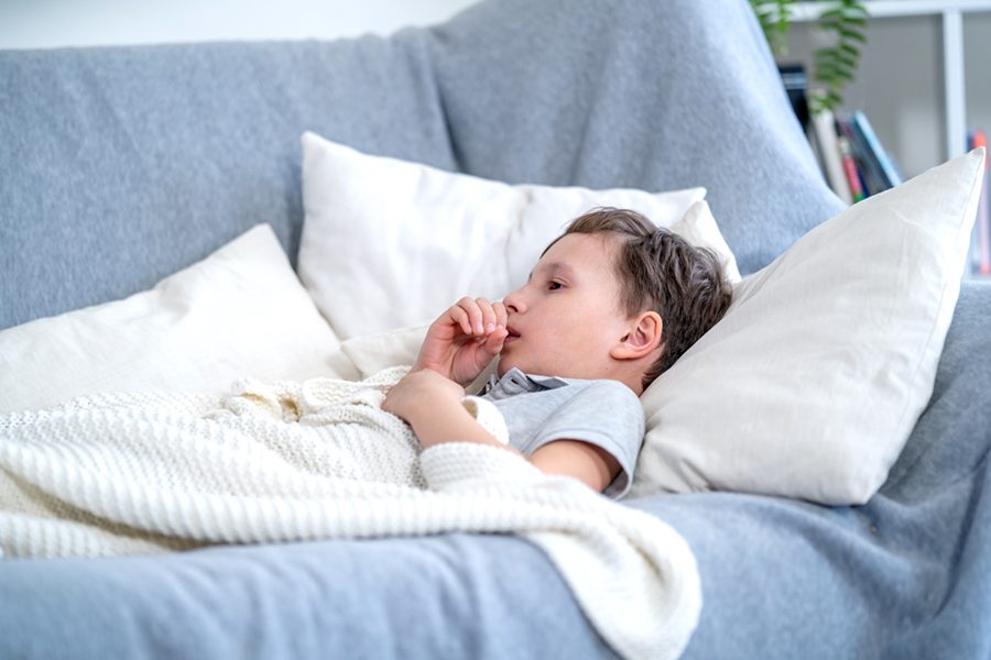 Sick boy tired from chest coughing having asthma, allergy. Cough during the epidemic of SARS, Pneumonia and influenza. Child Coughs Lying In Bed.