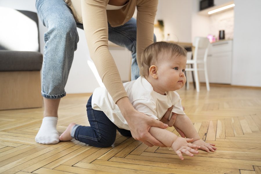 side-view-parent-helping-baby-crawl