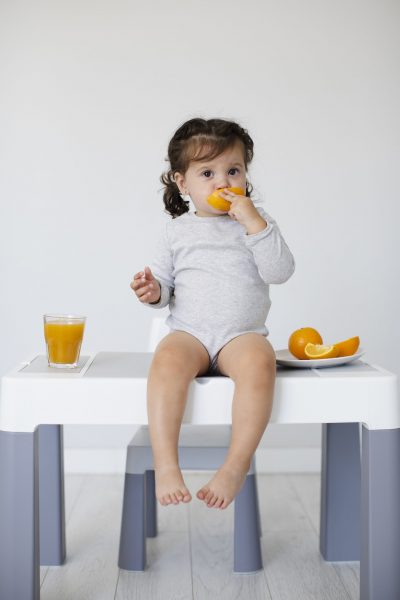 sitting-table-baby-girl-eating-orange