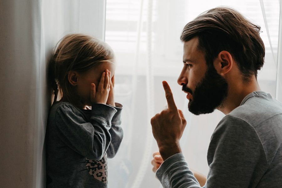 The father puts the child in a corner and makes remarks for bad behavior by waving his index finger near his face. The child does not want punishment and apologizes
