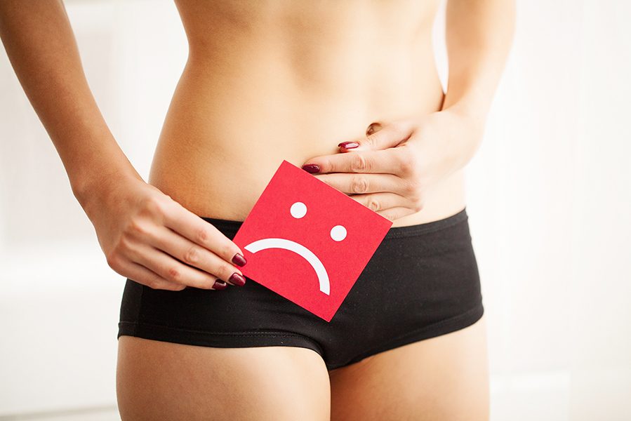 Vaginal or urinary infection and problems concept. Young woman holds paper with sad smile above crotch.