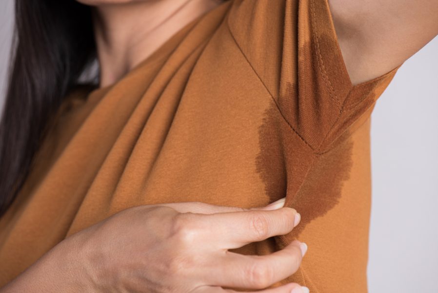 Close-up asian woman with hyperhidrosis sweating. Young asia woman with sweat stain on her clothes against grey background. Healthcare concept.