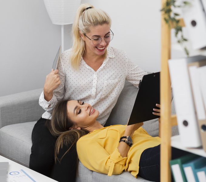 women-relaxing-sofa-looking-clipboard