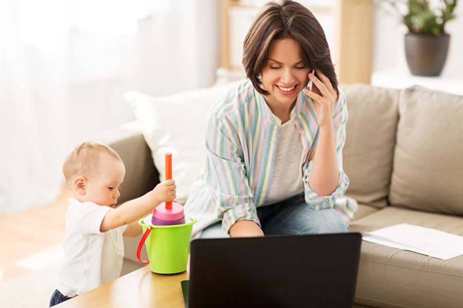 multi-tasking, freelance and motherhood concept - working mother with baby son calling on smartphone at home