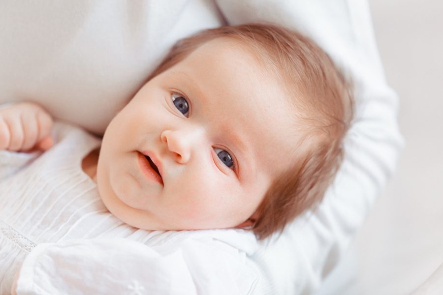 Young mother and newborn baby in white bedroom